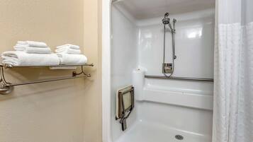 A bathroom with a bathtub, a towel rack with folded towels, and a shower with a handheld showerhead.
