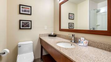 A bathroom with a white toilet, a sink with a mirror, and framed pictures on the wall.