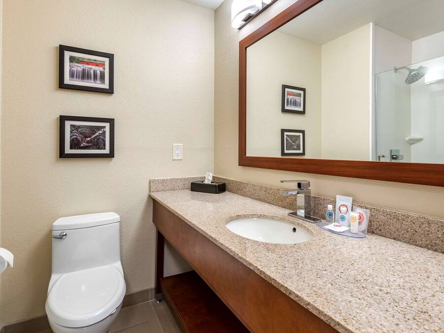 A bathroom with a white toilet, a sink with a mirror, and framed pictures on the wall.