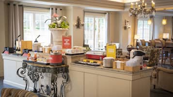 A hotel breakfast area with a buffet setup, including various food items and a caution sign for hot surfaces.