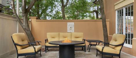 Un patio al aire libre con una mesa redonda, dos sillones y un sofá.