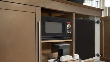 A kitchen area with a microwave, coffee maker, and a basket with items.