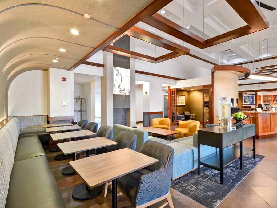 Un moderno vestíbulo de hotel con áreas de estar, un mostrador de recepción y un bar.