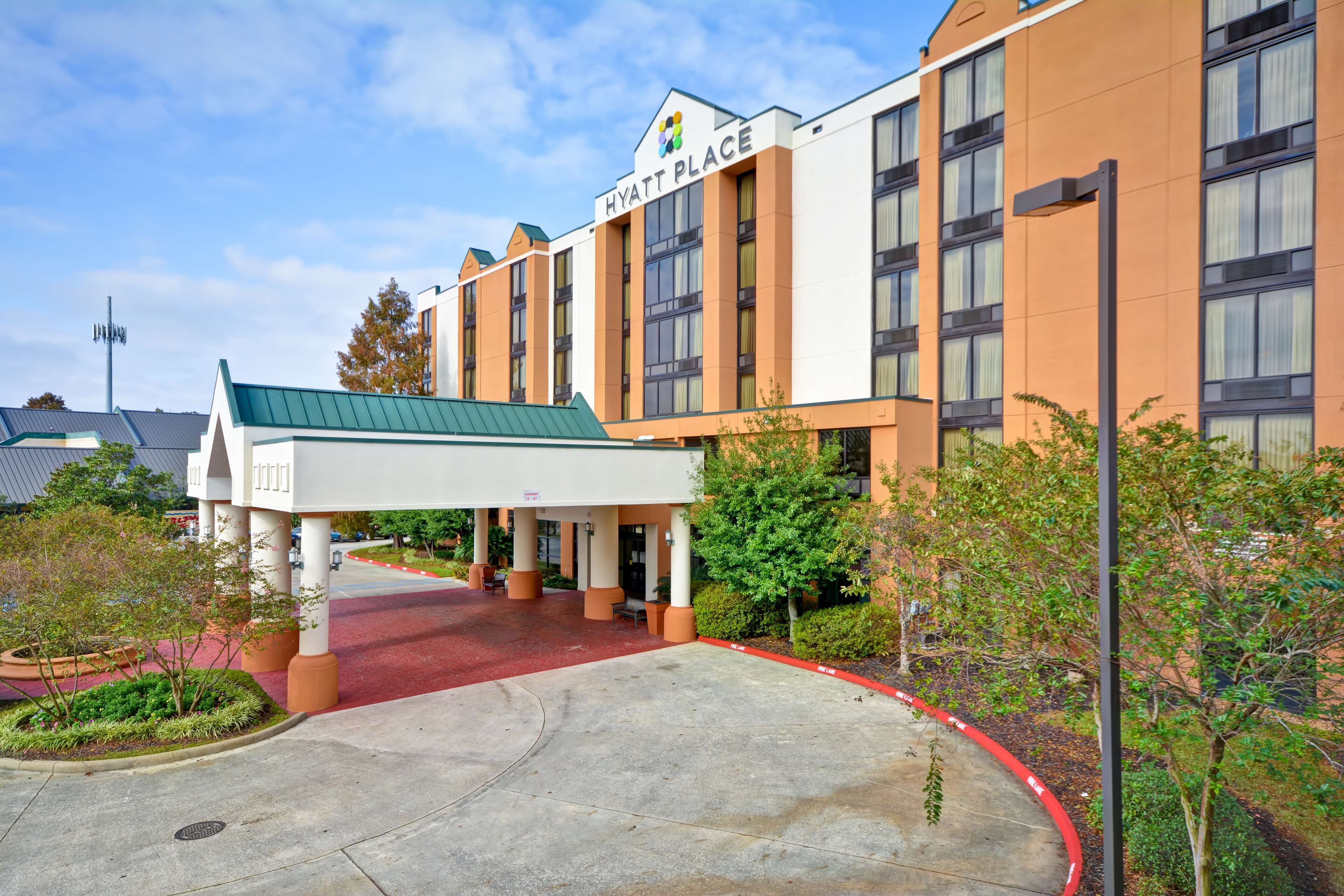 Un hotel Hyatt Place amb entrada coberta, catifa vermella i teulat verd.