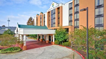 Un hotel Hyatt Place con entrada cubierta, alfombra roja y techo verde.