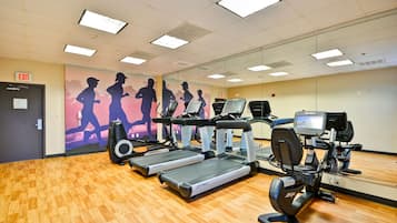 A gym with treadmills, exercise bikes, and a mirrored wall.