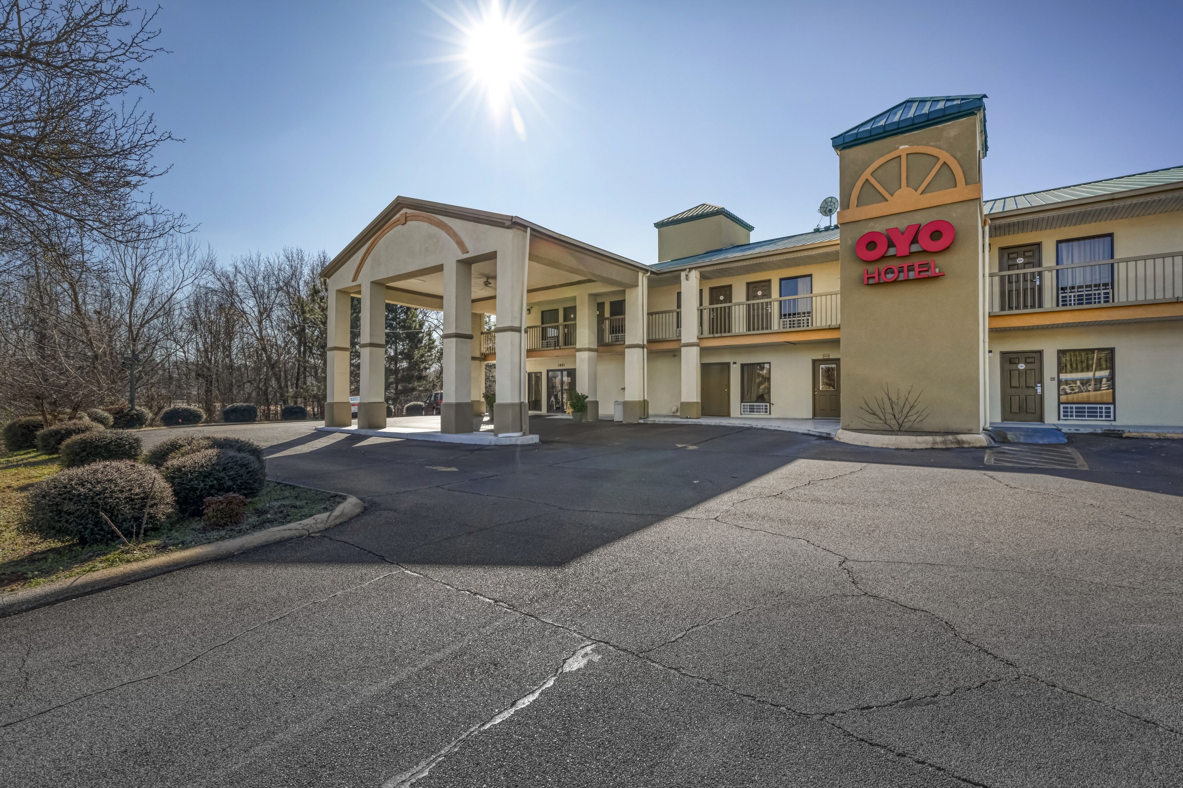 A hotel entrance with a covered parking area, a sign reading "OYO Hotel," and a clear sky.