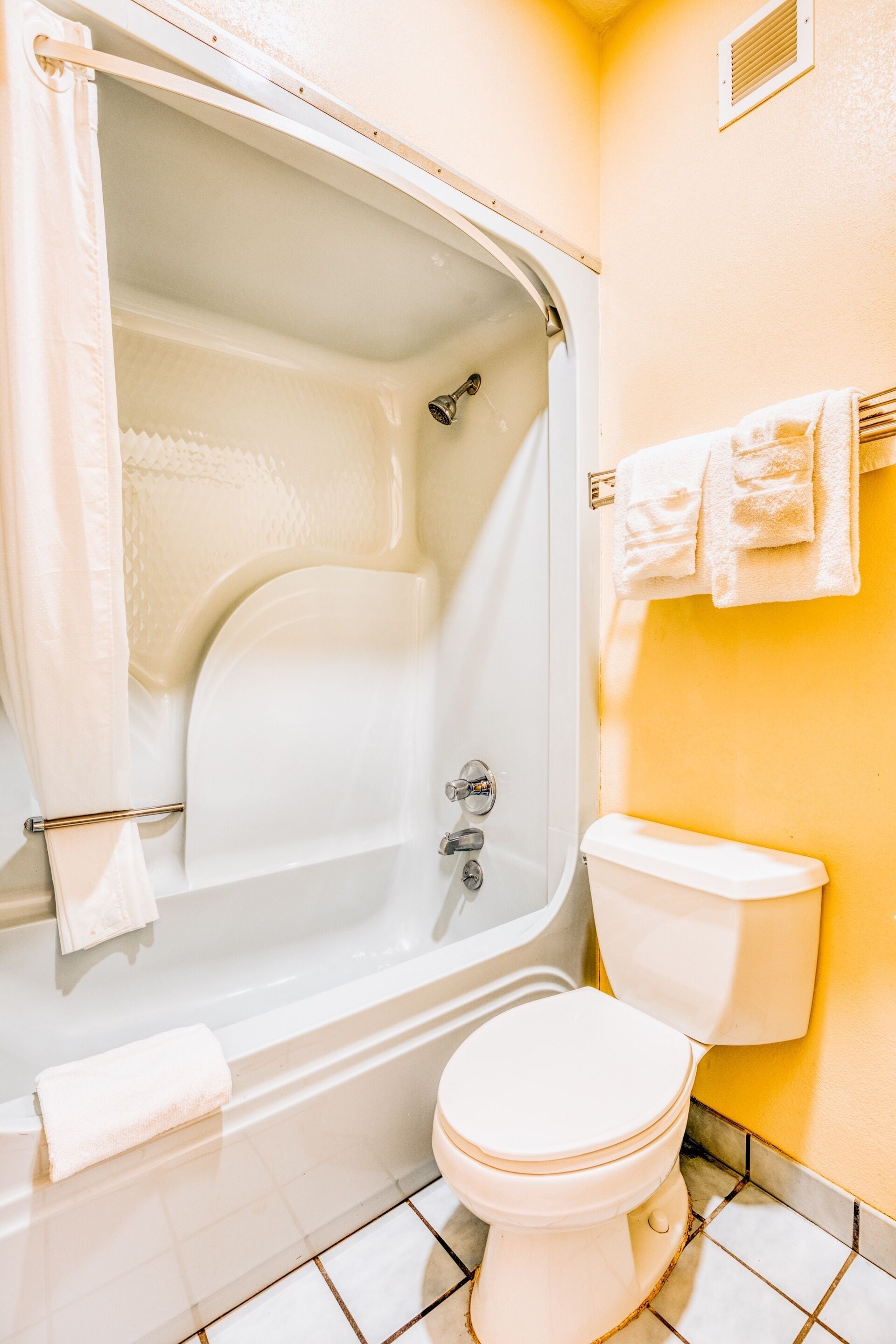 Un baño con bañera, inodoro y toallero.