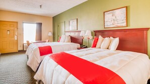 A hotel room with two beds, a wooden headboard, a painting on the wall, and a window with curtains.