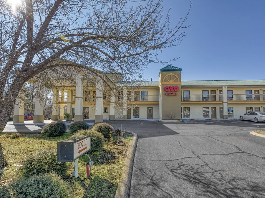 A hotel with a central tower, multiple balconies, and a parking lot.