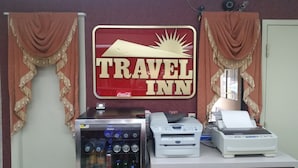 Balcão de agência de viagens com uma placa 'TRAVEL INN', um dispensador de bebidas e uma impressora.