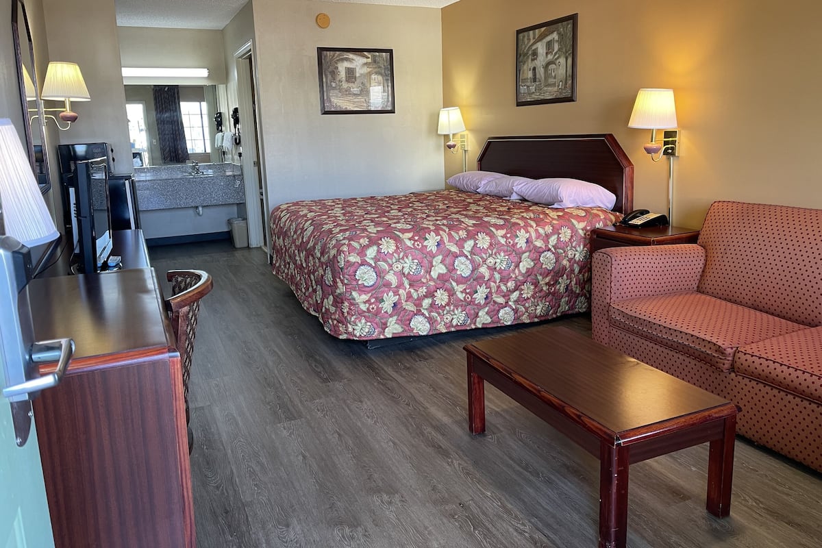 Ein Hotelzimmer mit Bett, Sofa, Schreibtisch und Fernseher.