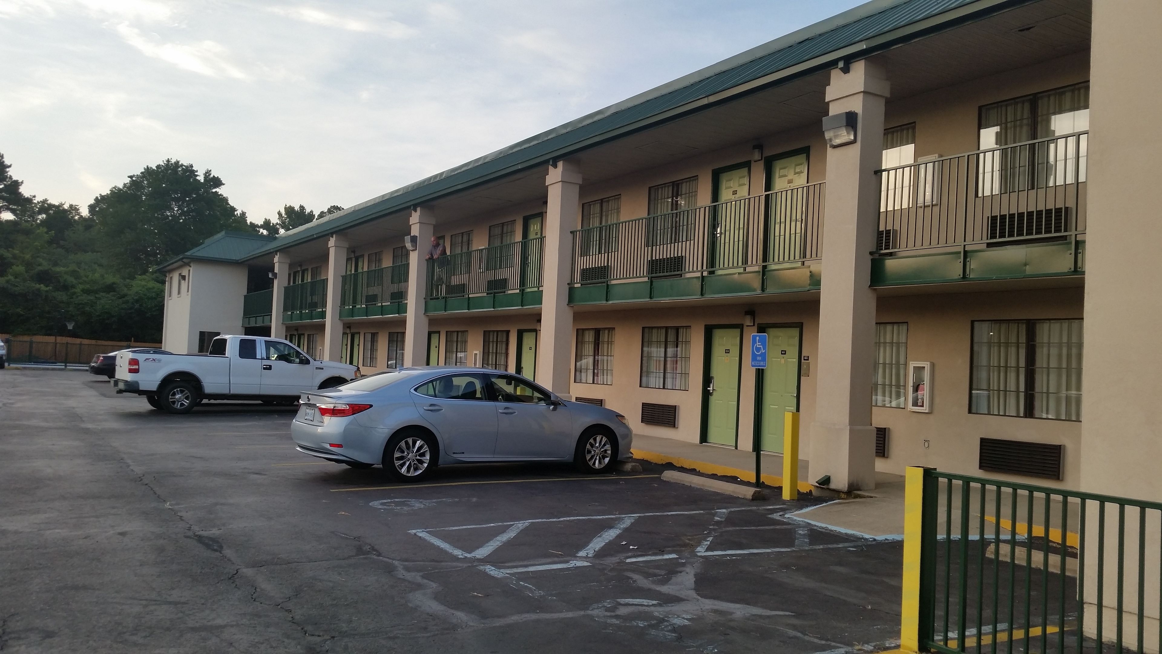 A motel with multiple floors, parking spaces, and a green railing.