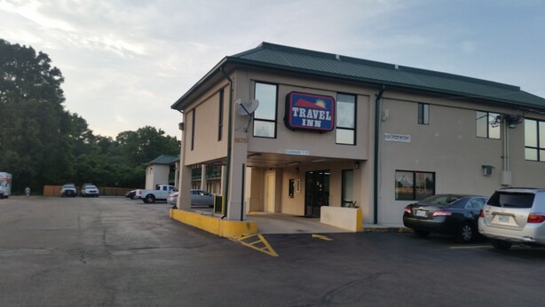 Edifício do Travel Inn com placa, estacionamento e vários carros estacionados.