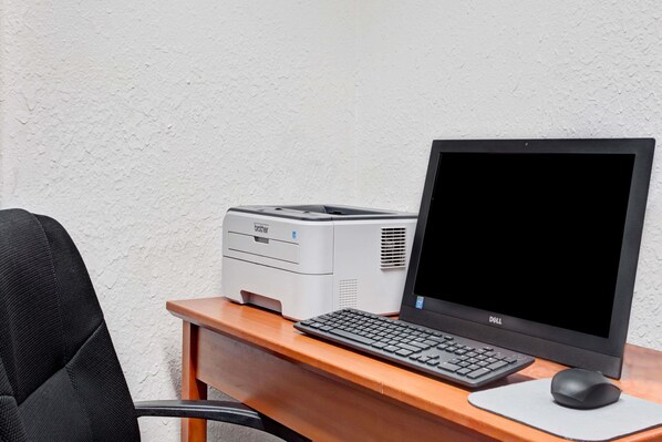 A desk with a desktop computer, a printer, and a chair.