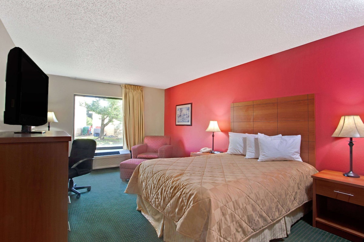 Una habitación de hotel con una cama, un escritorio, una silla y un televisor.