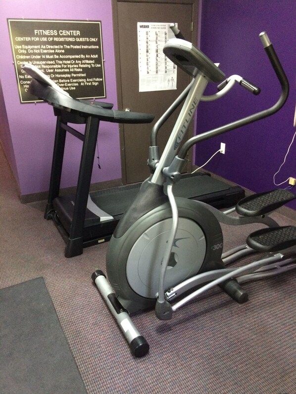 A fitness center with an elliptical machine, a treadmill, and a stationary bike. There is a sign on the wall with rules for using the equipment. - Ramada by Wyndham Pearl/Jackson Airport (Pearl)