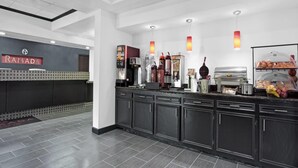A modern kitchen area with a coffee station, a refrigerator, and a display case with baked goods. - Ramada by Wyndham Pearl/Jackson Airport (Pearl)