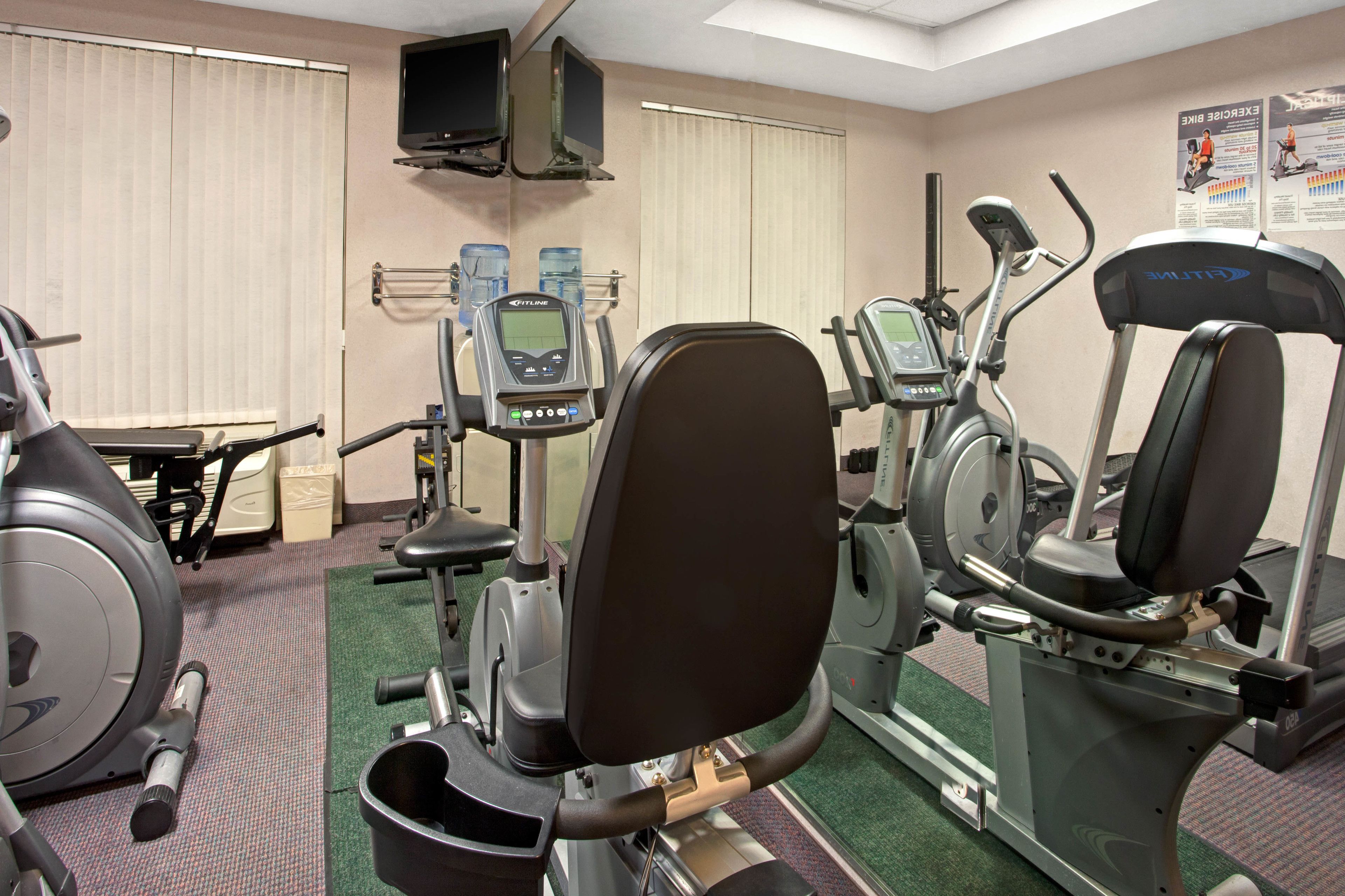 A hotel gym with various exercise equipment, including a treadmill, stationary bike, and weight machines.