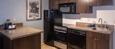A modern kitchen with dark wood cabinets, a stainless steel refrigerator, a microwave, an oven, and a dishwasher.