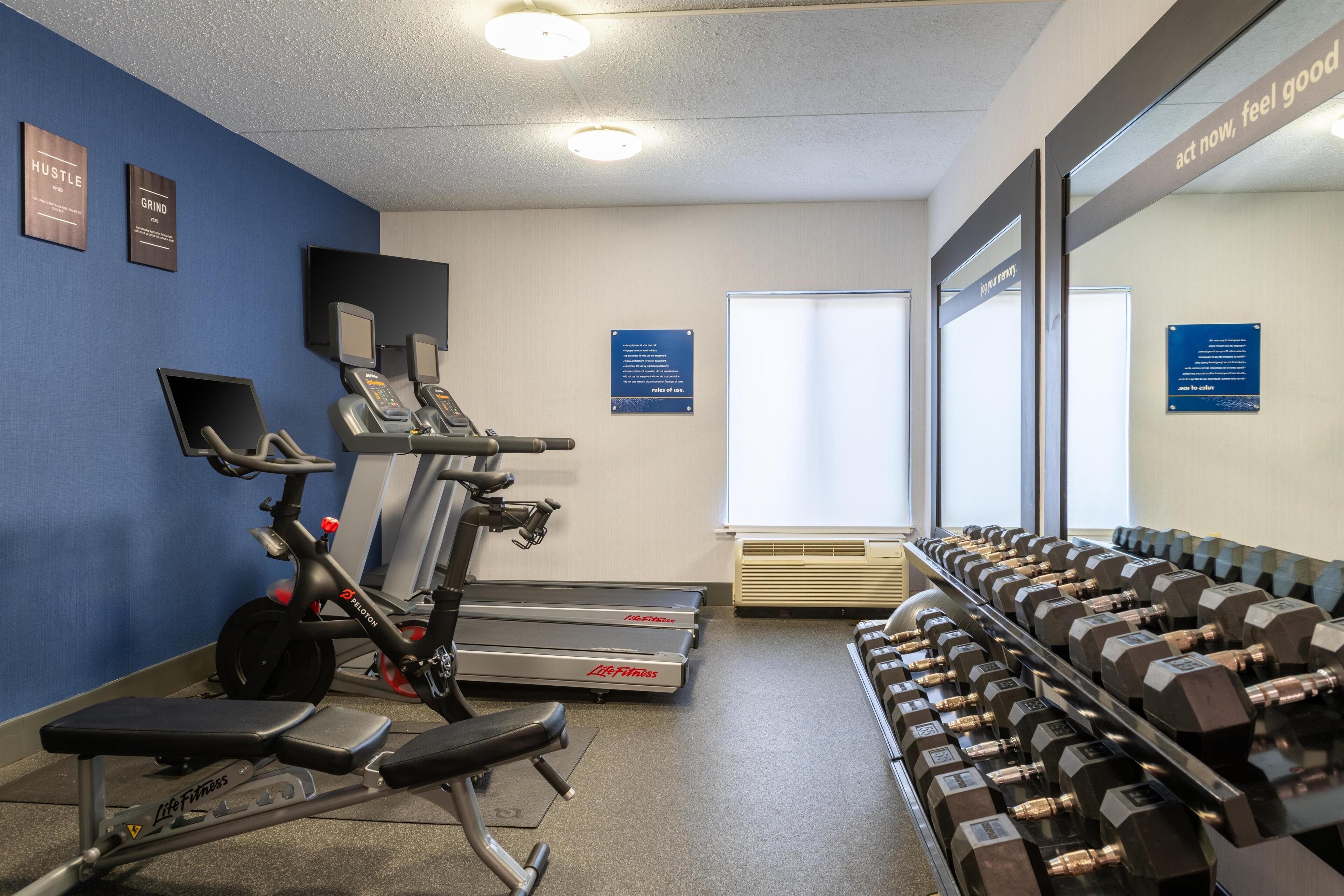 Un gimnasio con cintas de correr, una bicicleta estática y una zona de press de banca.
