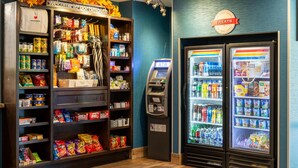 Zona de quioscos de autoservicio con aperitivos, una caja registradora y dos dispensadores de bebidas.