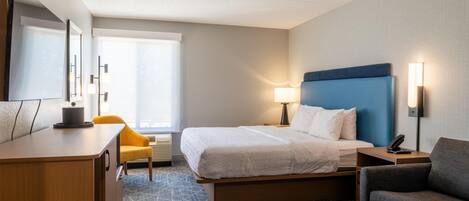 Una habitación de hotel con cama, escritorio, silla, sofá y lámpara.