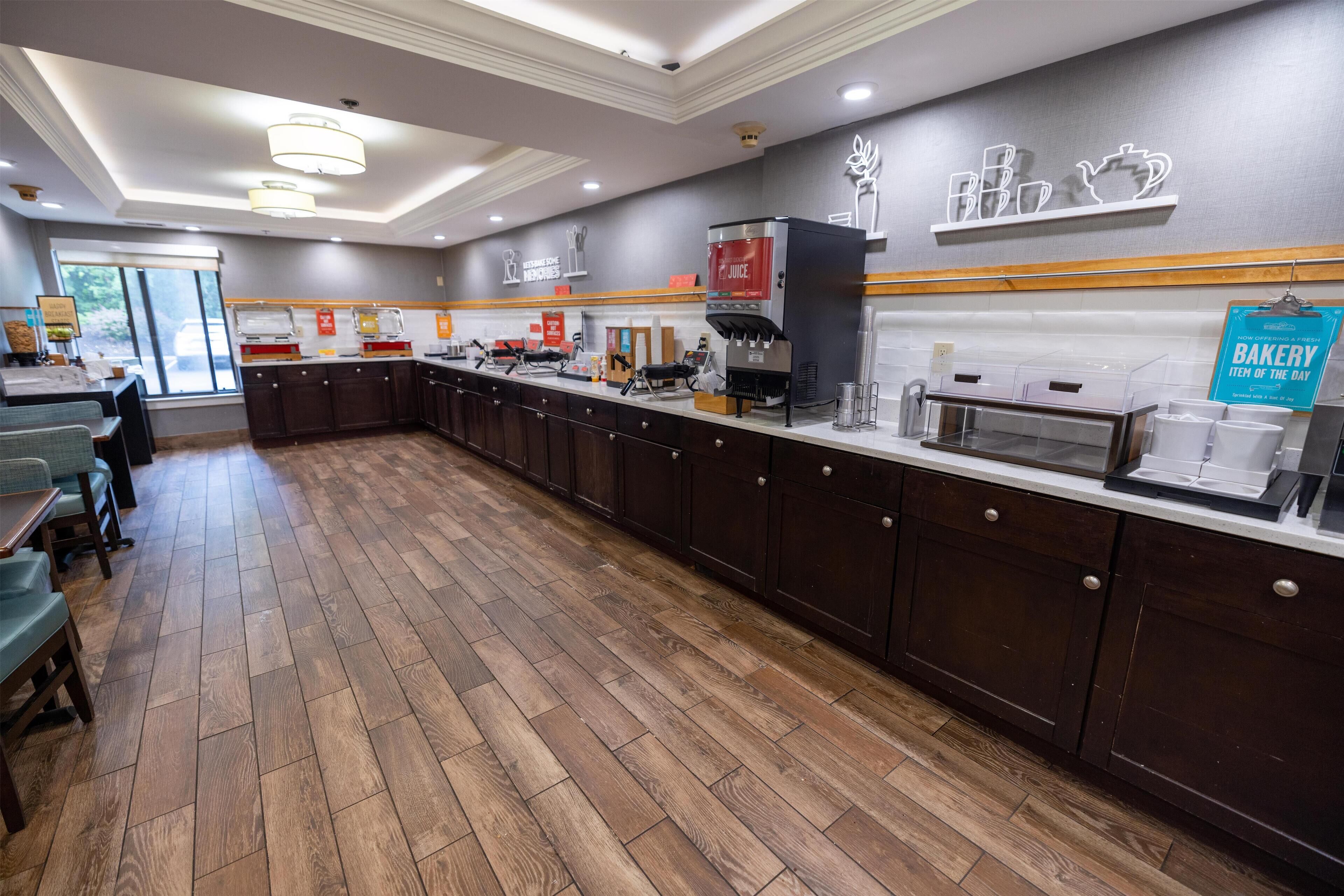 A modern kitchen area with wooden flooring, a coffee station, and a bakery sign.