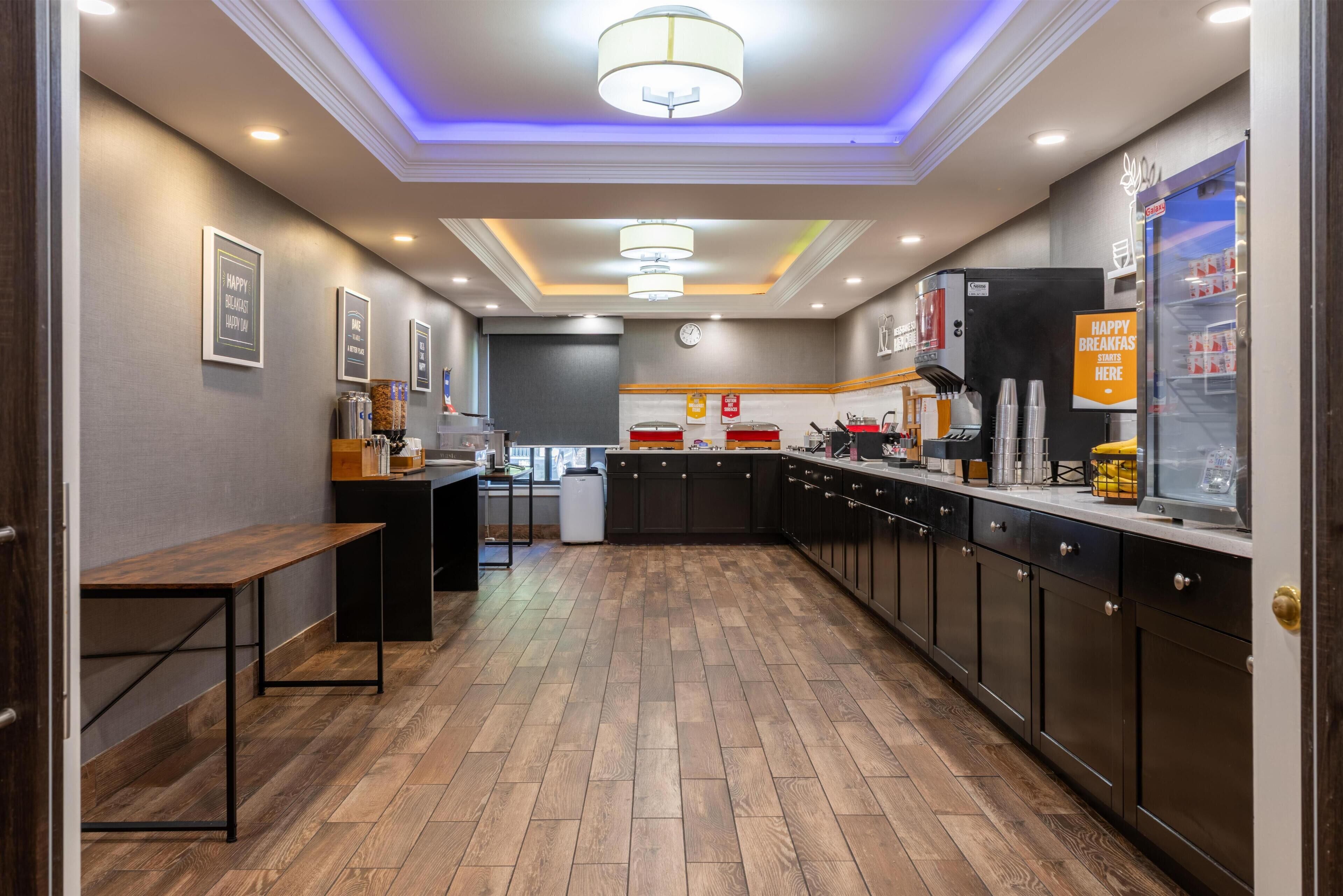 A modern kitchen with wooden flooring, dark cabinets, and a central island.