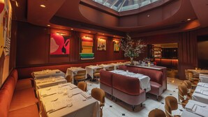 A restaurant with a high ceiling, a skylight, and multiple dining areas with tables and booths.