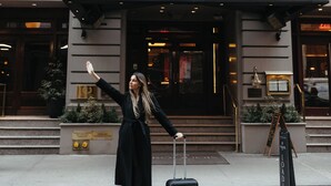 A building with a sign reading 'IROQUOIS' at the entrance, a black awning, and a person with a suitcase.