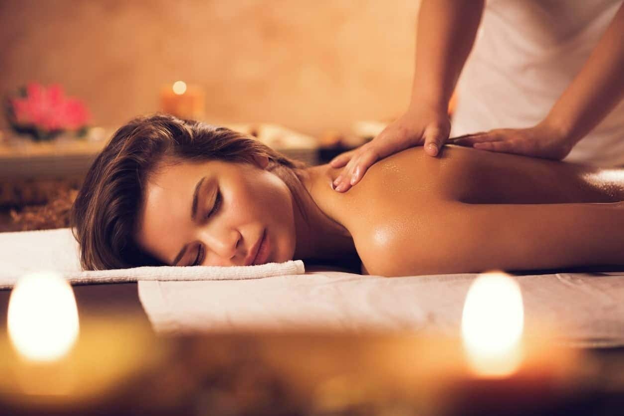 En person modtager en massage på ryggen i en spa-lignende atmosfære.