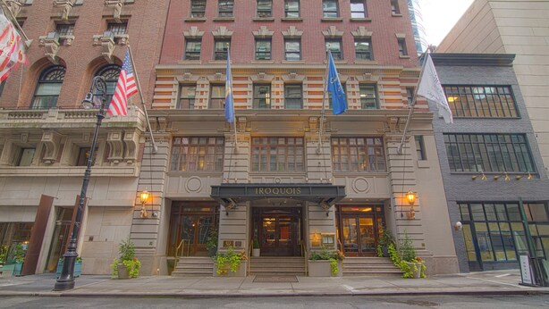 A historic building with a classic facade, multiple flags, and a prominent entrance.