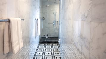 A modern bathroom with a glass-enclosed shower, a patterned floor, and a towel rack.
