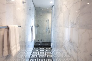 Een moderne badkamer met een douchecabine van glas, een vloer met een patroon en een handdoekhouder.