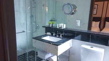Un baño moderno con ducha de vidrio, lavamanos de mármol y un inodoro.