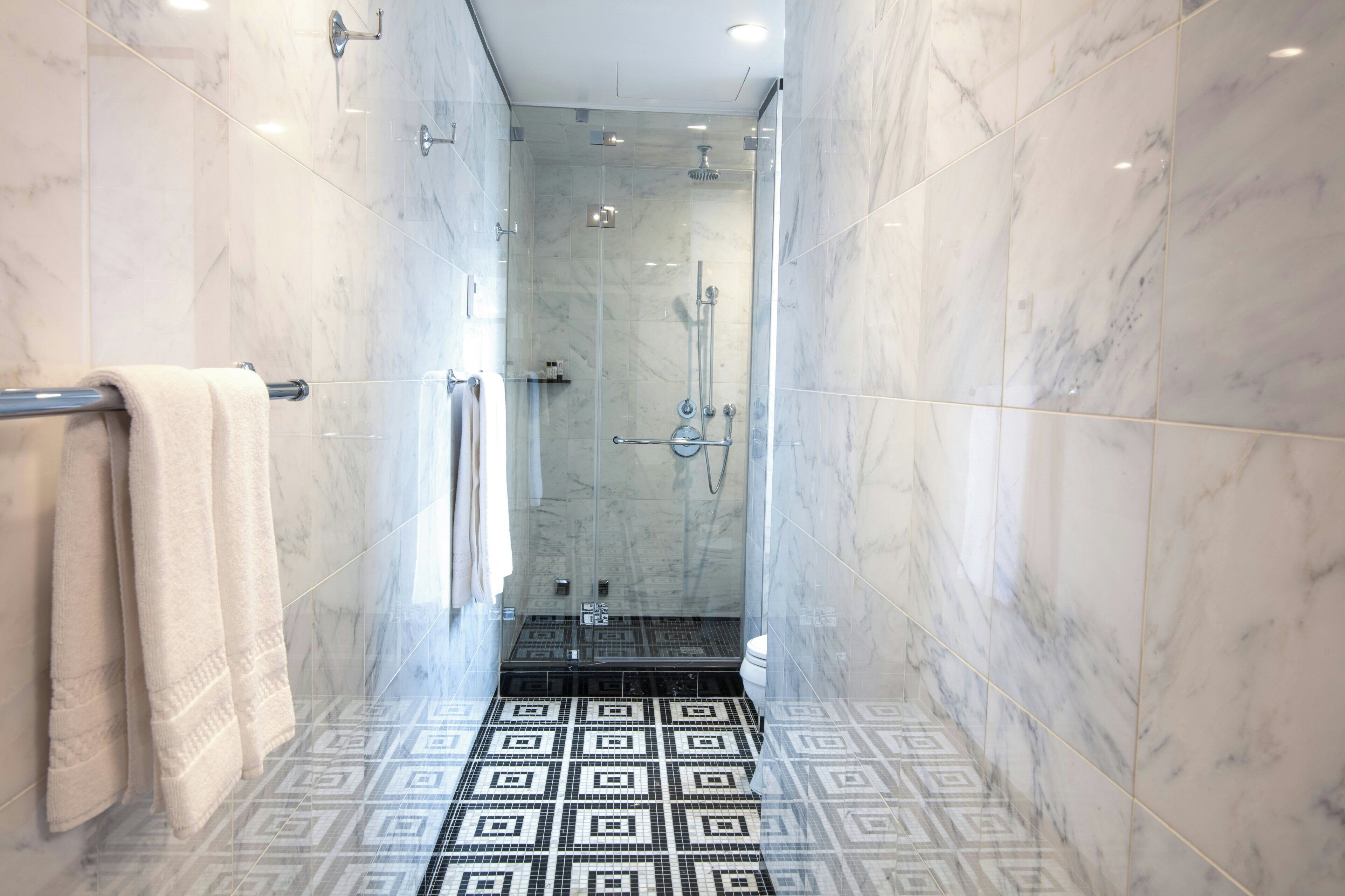 A bathroom with a shower, a toilet, and a patterned floor.