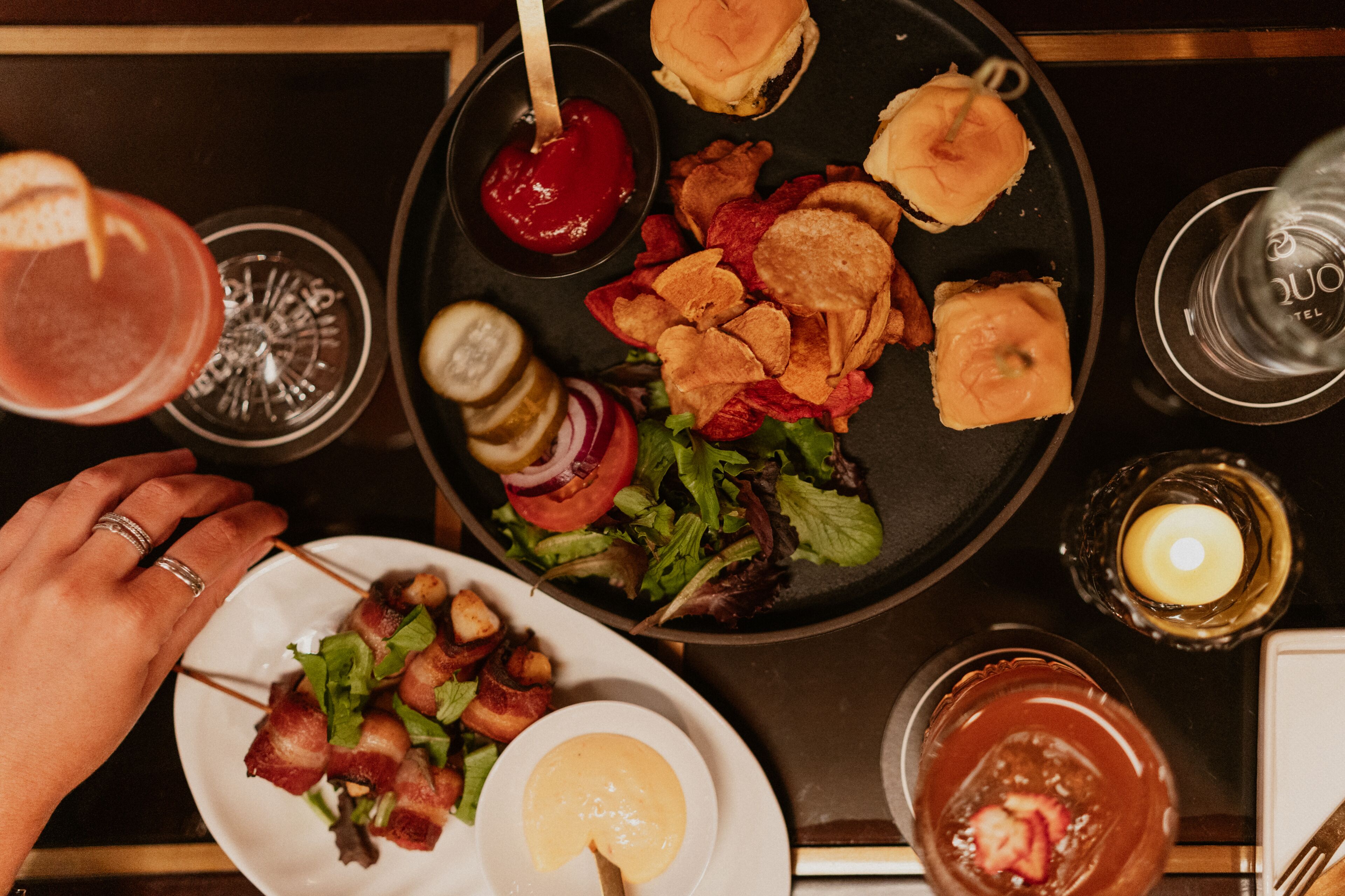 A dining table with a plate of food, a salad, and a burger.