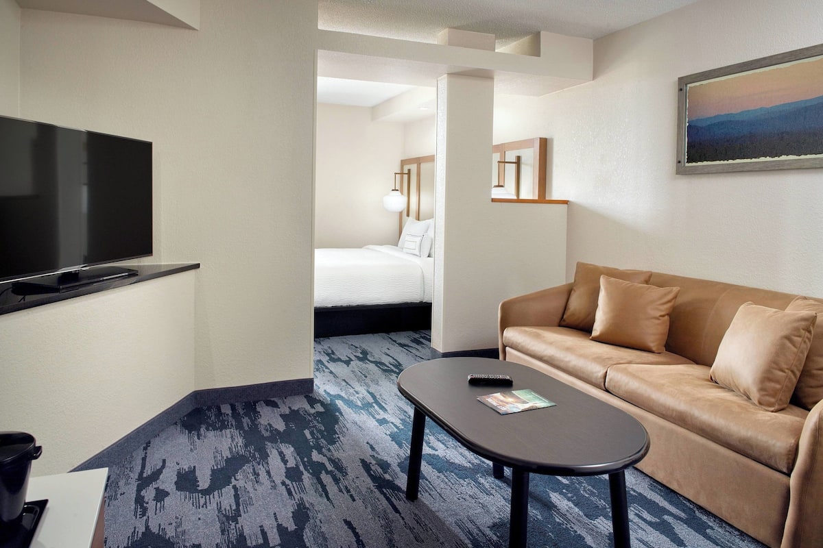 Een hotelkamer met een flatscreen televisie, een bank, een salontafel en een bed met hoofdeinde.