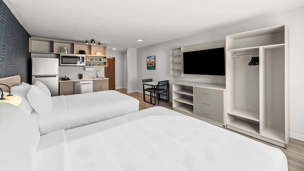 Et moderne hotelværelse med en stor seng, et tekøkken, et fjernsyn og et garderobeskab.