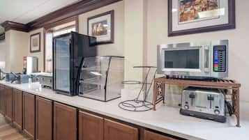 Eine Hotelküche mit Kühlschrank, Mikrowelle, Toaster und einer Vitrine.