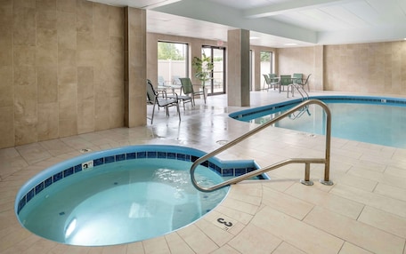 A swimming pool with a blue tiled edge, a metal ladder, and a tiled floor.