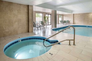 A swimming pool with a blue tiled edge, a metal ladder, and a tiled floor.