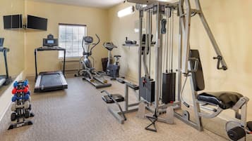 A gym with treadmills, elliptical machines, weight machines, and a bench press.