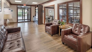 A lobby with a brown leather sofa, a small round table with a plant, and a glass door leading outside. - Best Western Mason Inn (Mason)