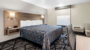 A hotel room with a bed, bedside table, lamp, and a window with blinds. - SureStay Hotel by Best Western Duncan (Duncan)