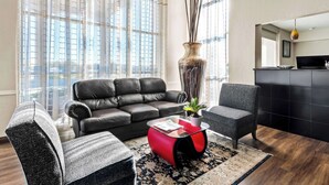 A modern living room with a leather sofa, a glass coffee table, and a grey armchair. - SureStay Hotel by Best Western Duncan (Duncan)