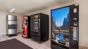 A room with a refrigerator, a vending machine, and a water dispenser.