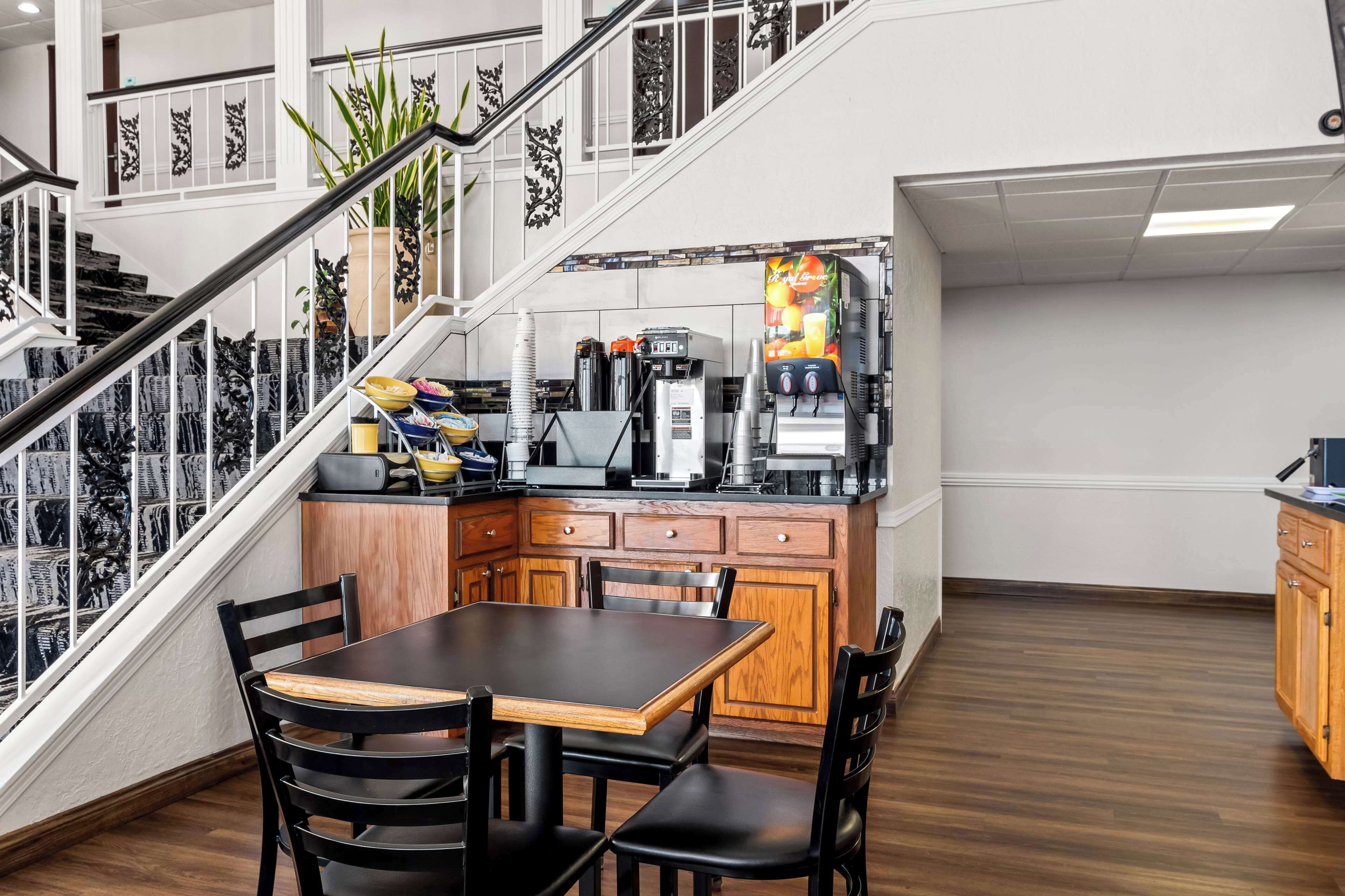 Une cuisine moderne avec une table et des chaises en bois, un appareil à café et un escalier agrémenté de rampes décoratives.