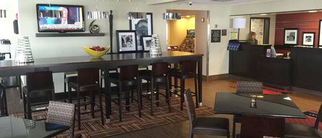 A hotel lobby with a reception desk, bar area, and seating arrangements.